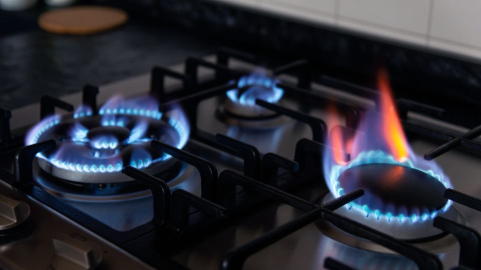 Nahaufnahme eines Gasherds mit brennenden Flammen in verschiedenen Farben.