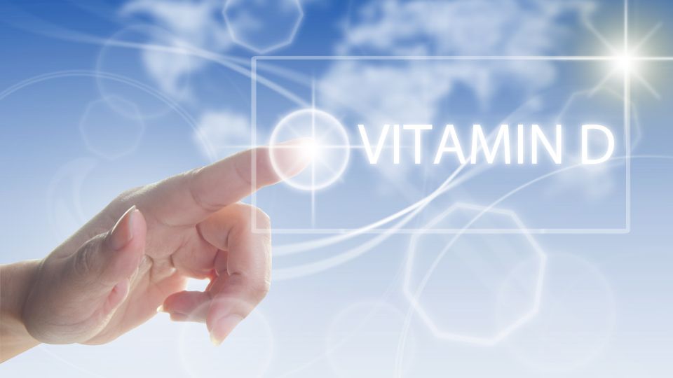 Eine Hand zeigt auf den Begriff Vitamin D vor einem blauen Hintergrund.