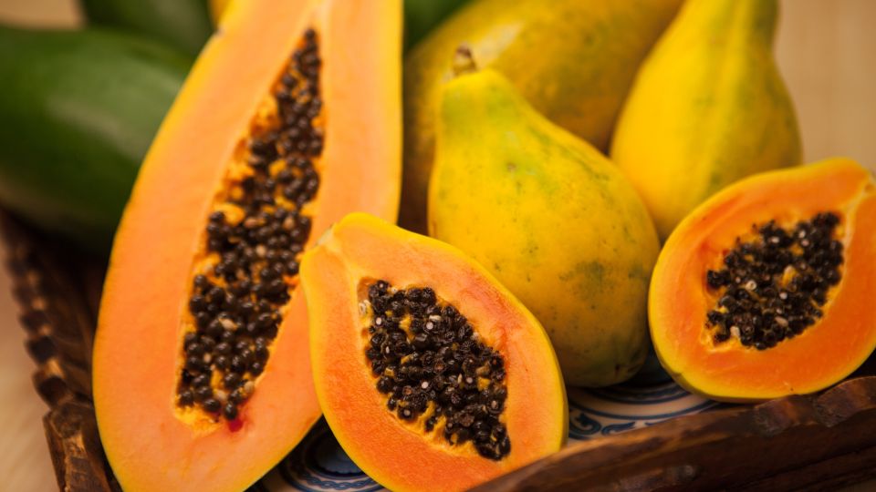 Frische Papayas mit leuchtendem Fruchtfleisch und schwarzen Kernen auf einem Tablett.
