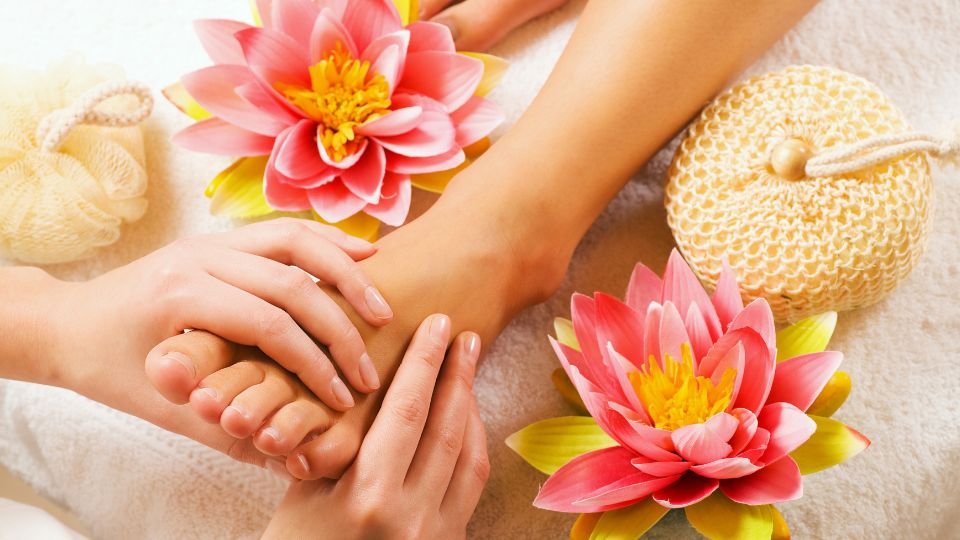 Eine entspannende Fußreflexzonenmassage mit Blumen und Pflegeprodukten.