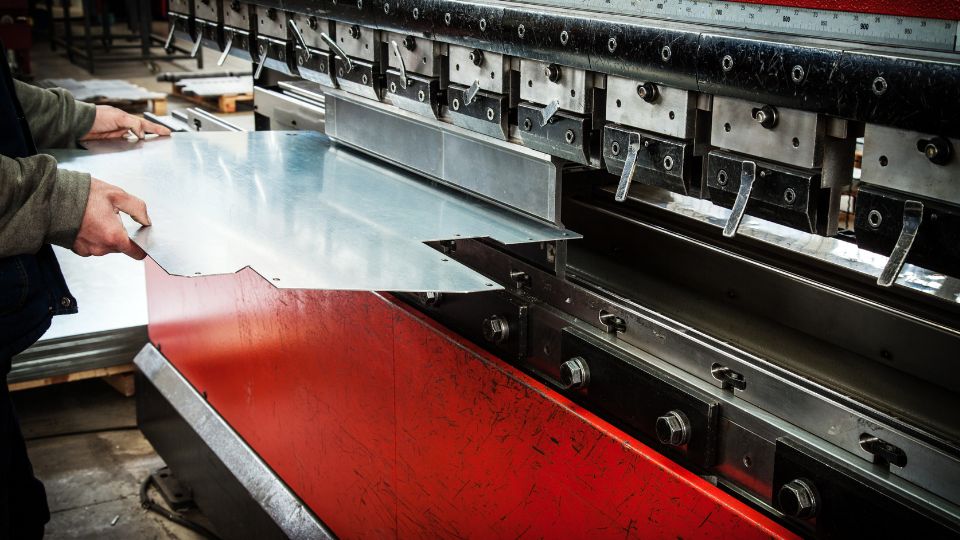 Ein Arbeiter platziert ein Metallblech in eine CNC-Abkantpresse zur Bearbeitung.
